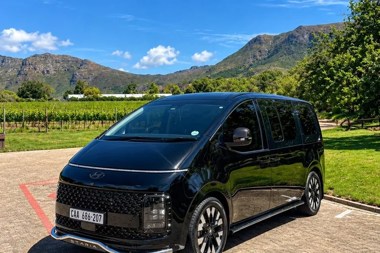 Black Hyundai Staria Luxury parked at a Cape Winelands estate, vineyards and mountains behind